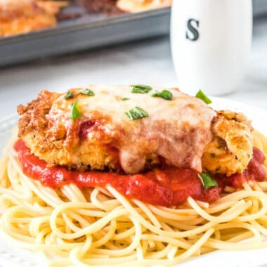 Baked Chicken Parmesan is coated in savory breadcrumbs & topped with gooey cheese. It’s an easy Italian-style dish perfect date night dinner or family meal!