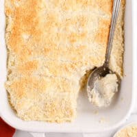 serving spoon in a pan of baked garlic mashed potatoes with recipe name at the bottom