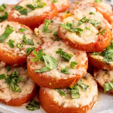 square image of baked parmesan tomatoes piled up on a plate
