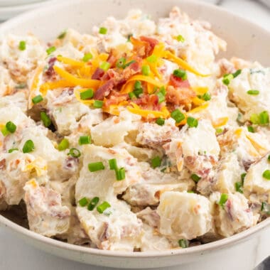 square image of baked potato salad in a serving bowl
