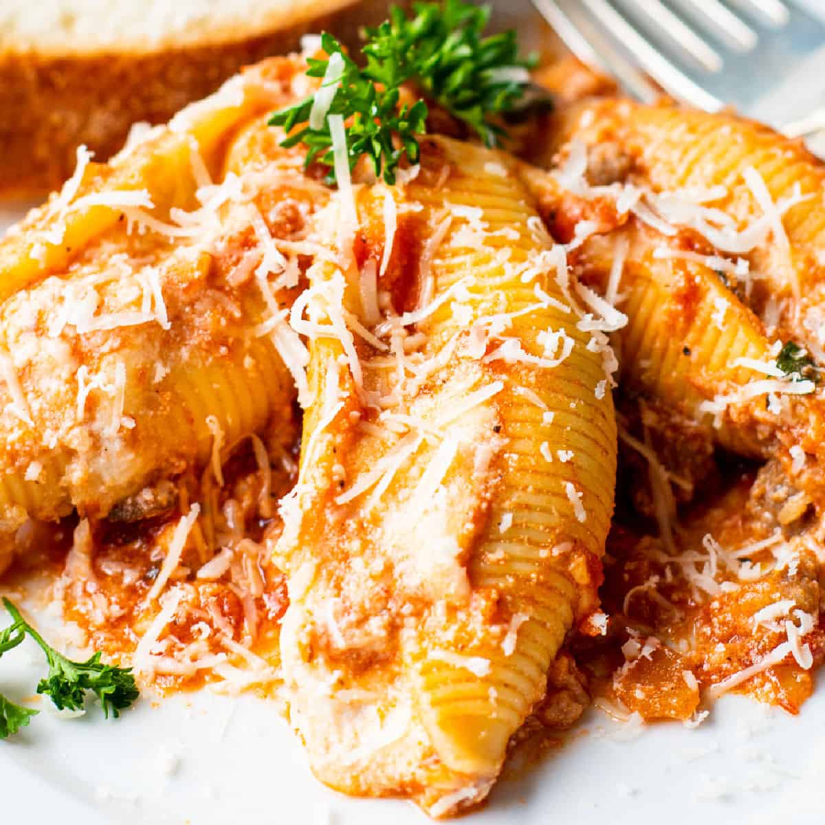 square image of stuffed shells on a plate with parmesan and parsley