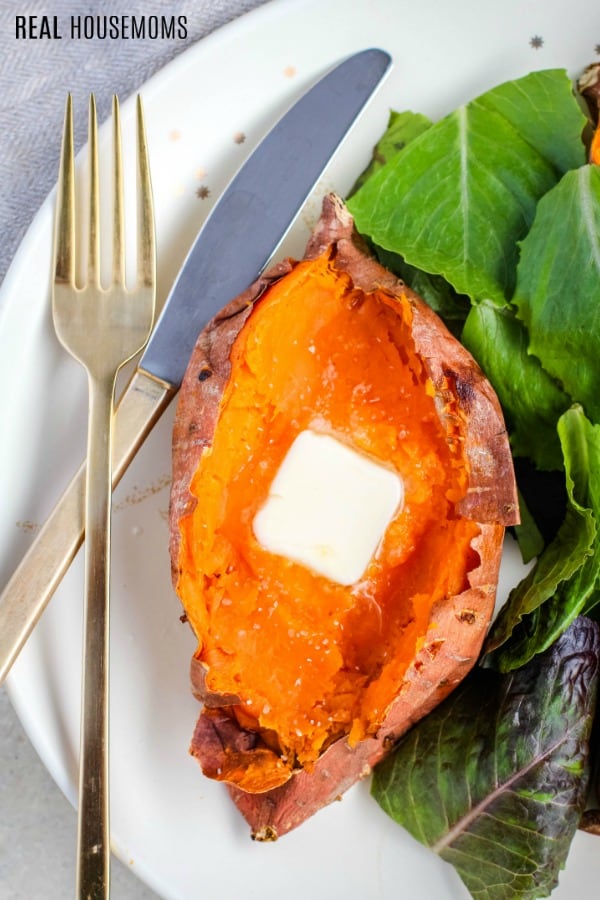 baked sweet potato served with green salad and topped with butter