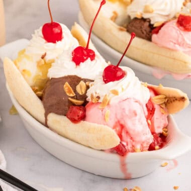 square image of a banana split with sauces, whipped cream, cherries, and peanuts