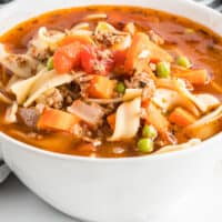 square image of beef noodle soup in a white bowl