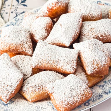 square image of beignets piled on a plate
