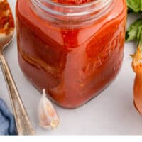 best ever pizza sauce in a jar with a basil leaf with recipe name at the bottom