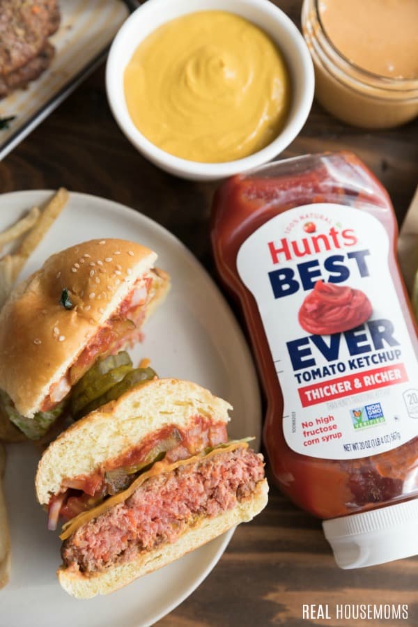 burger cut in half on a plate next to a hunt's best ever ketchup bottle