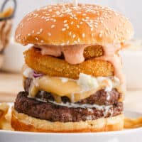 square image of a big daddy double cheeseburger with boom boom sauce on a plate with a skewer stuck in the top
