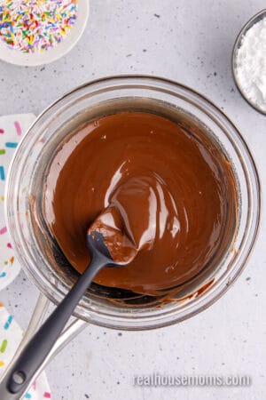 melted chocolate in the glass bowl of a double boiler, with a rubber spatula