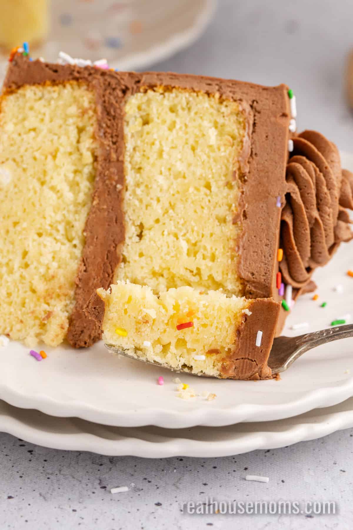 bite of birthday cake on a fork resting on the plate with the slice of cake