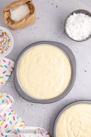 homemade yellow cake batter divided between two floured and greased round cake pans