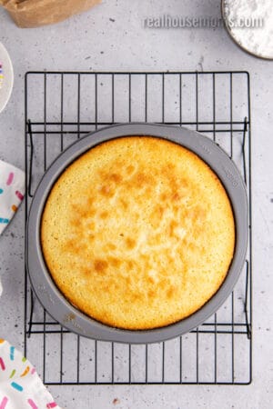 baked yellow cake in the cake pan on a wire rack