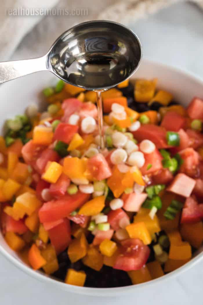 oil being added to a mixing bowl for black bean salad