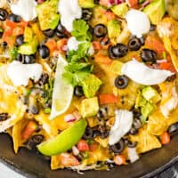 black bean and chicken nachos in a cast iron skillet with recipe name at the bottom