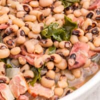 black eyed peas & collard greens in a white serving bowl with recipe name at the bottom