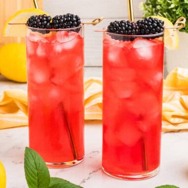 square image of two blackberry lemonades with sraws and blackberries as garnish