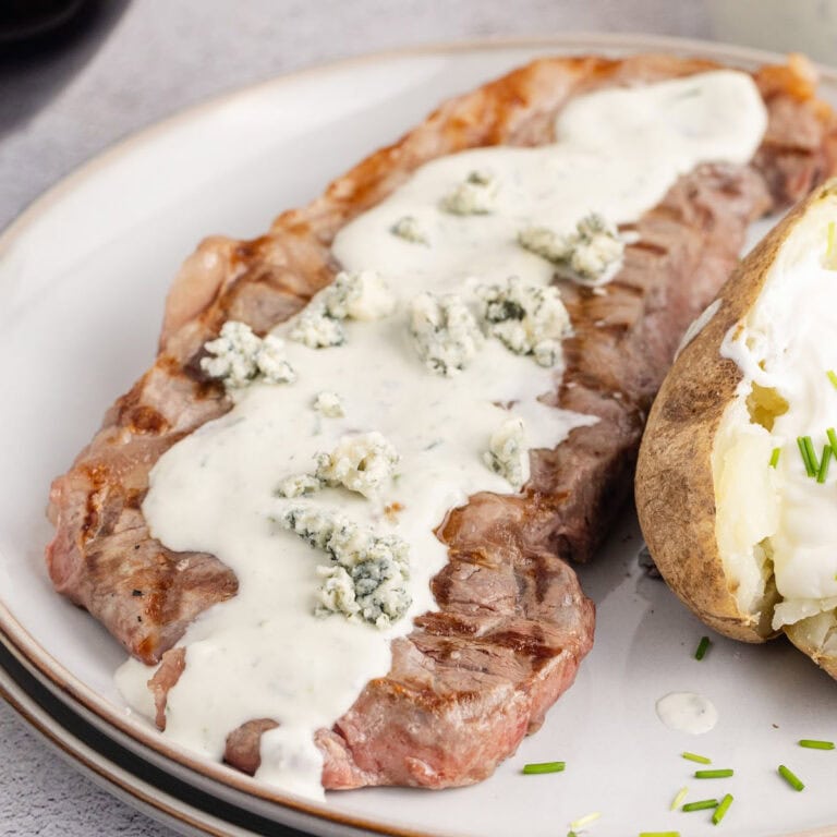square image of a steak topped with blue cheese sauce and blue cheese crumbles