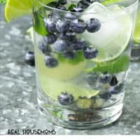 Glass filled with blueberries mint and lime