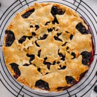 square image of blueberry pie with star spangled crust on a wire rack