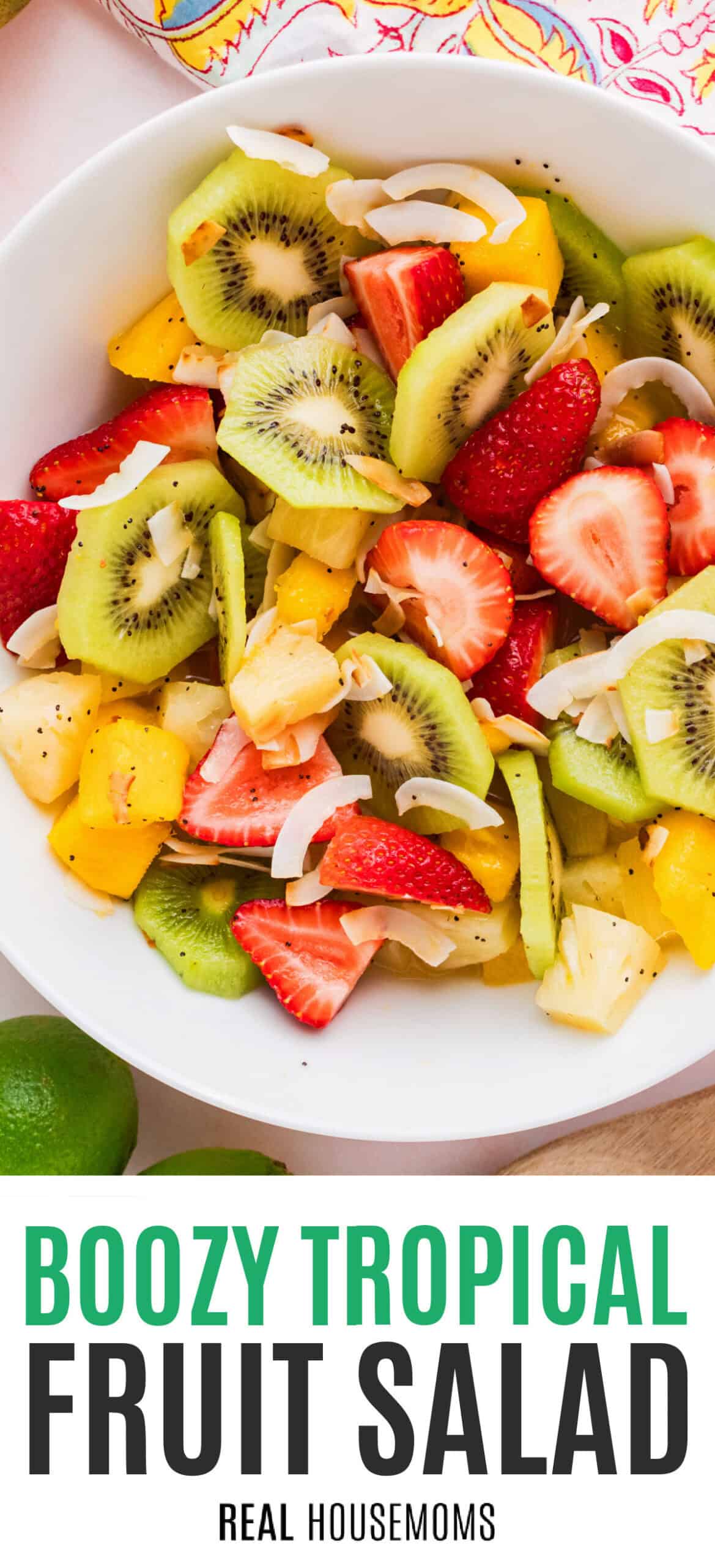 boozy tropical fruit salad in a white serving bowl with recipe name at the bottom