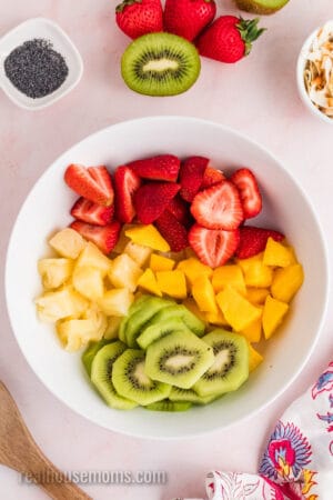 cut up fruits in a white mixing bowl