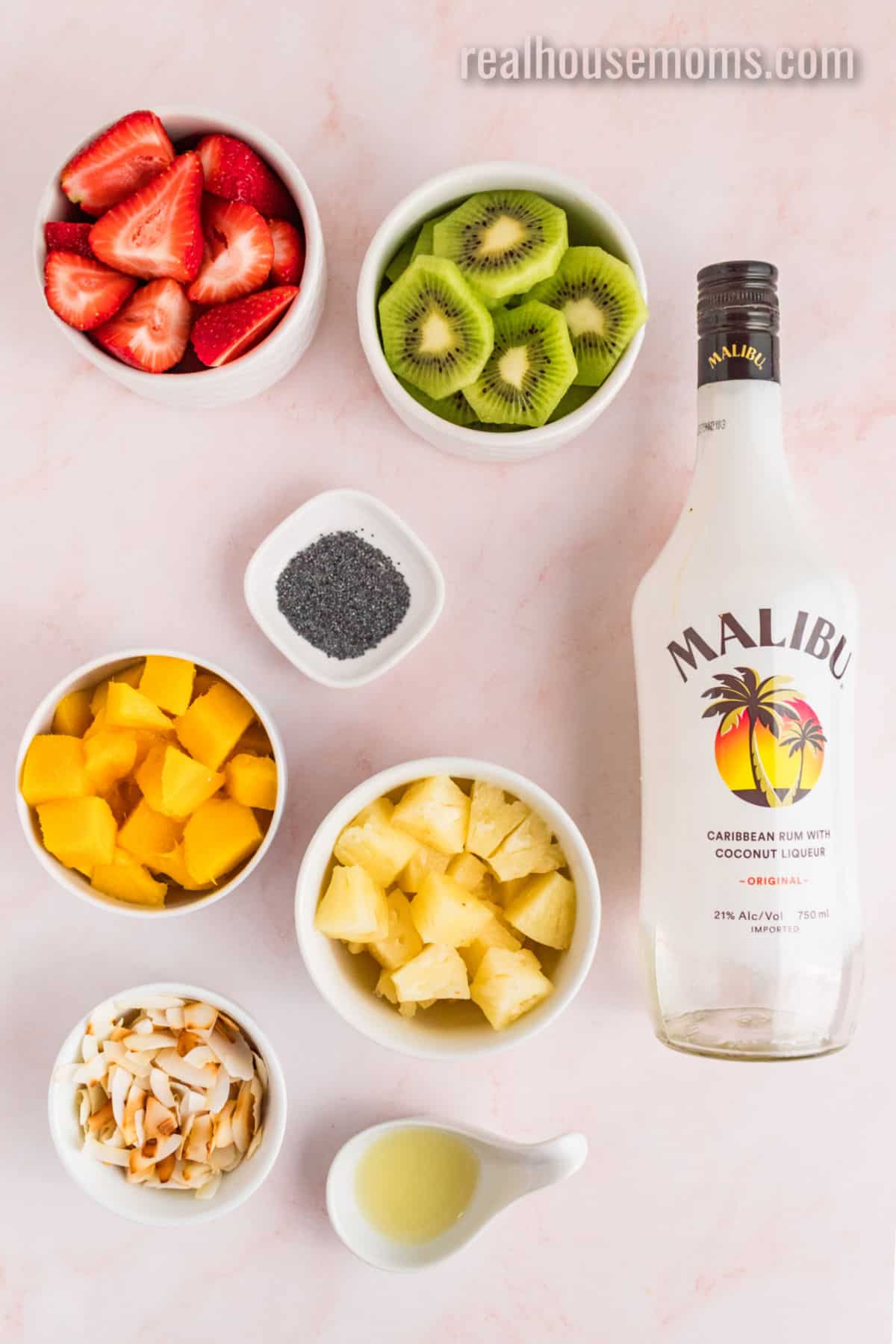 ingredients to make boozy fruit salad in bowls on a counter