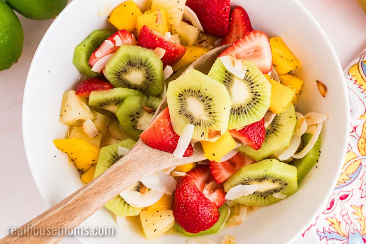 closeup of a spoonful of boozy tropical fruit salad over the serving bowl