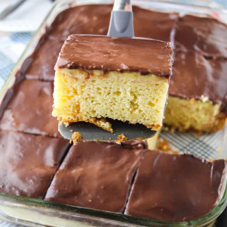 square iamge of a slice of boston cream poke cake on a spatula over the cake