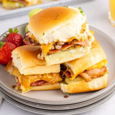 square image of three breakfast sliders arranged on a small plate with fresh fruit