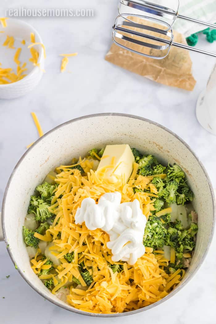 broccoli, cheese, butter, and sour cream in a pot with boiled potatoes