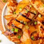 square close up image of brown sugar pineapple chicken on a platter with grilled pineapple slices