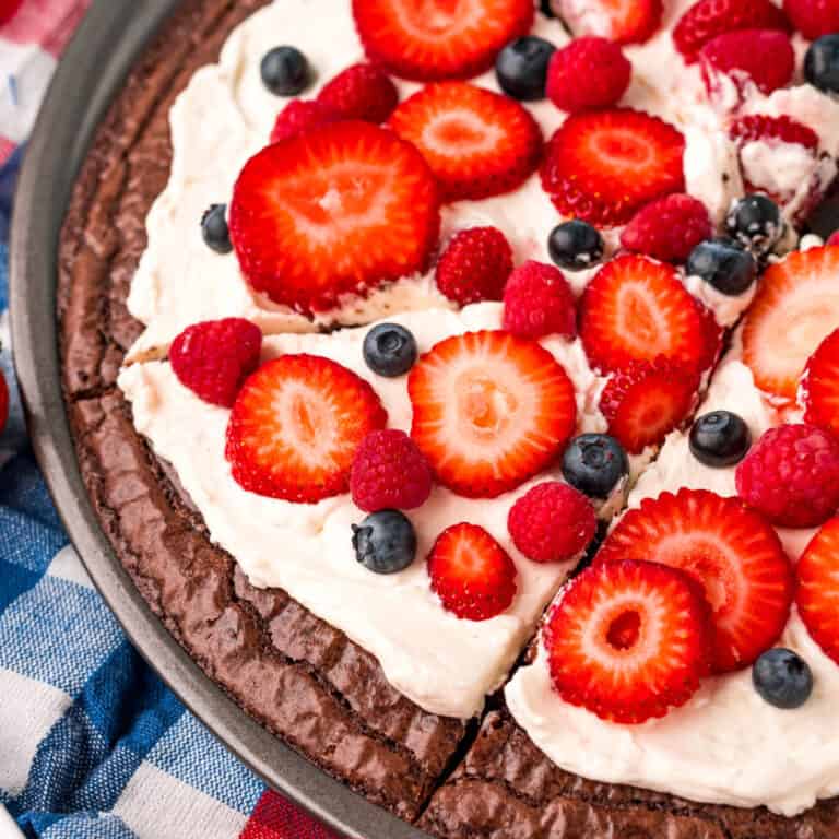 square image of brownie fruit pizza cut into slices