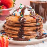 square image of brownie pancakes with whipped cream, chocolate sauce, and sprinkles