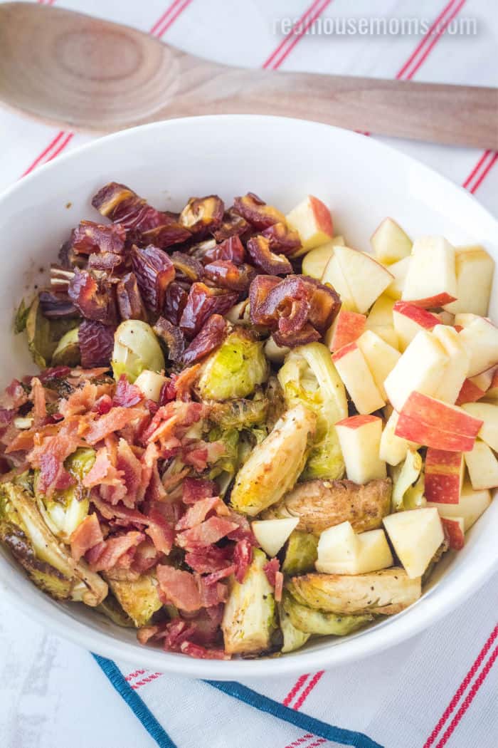 roasted brussels sprouts, bacon, dates, and apples in a serving bowl