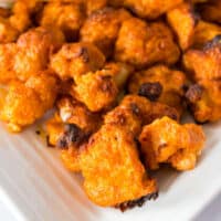 buffalo cauliflower bites on a plate with ranch dressing and celery sticks