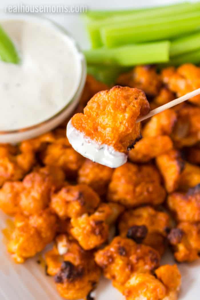 buffalo cauliflower bite on a toothpick dipped in dressing