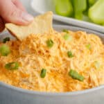 square image of a tortilla chip being dipped into a bowl of crock pot buffalo chicken dip