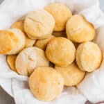 square image of buttermilk biscuits in a tea towel lined basket