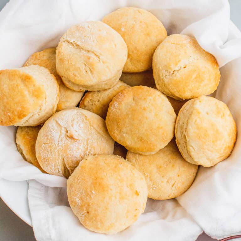 square image of buttermilk biscuits in a tea towel lined basket
