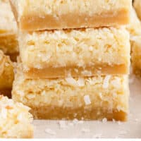 three coconut bars in a stack with recipe name at the bottom