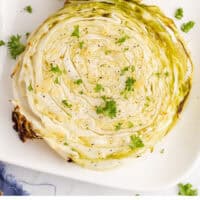 cabbage steaks on a platter with chopper parsley with recipe name at the bottom