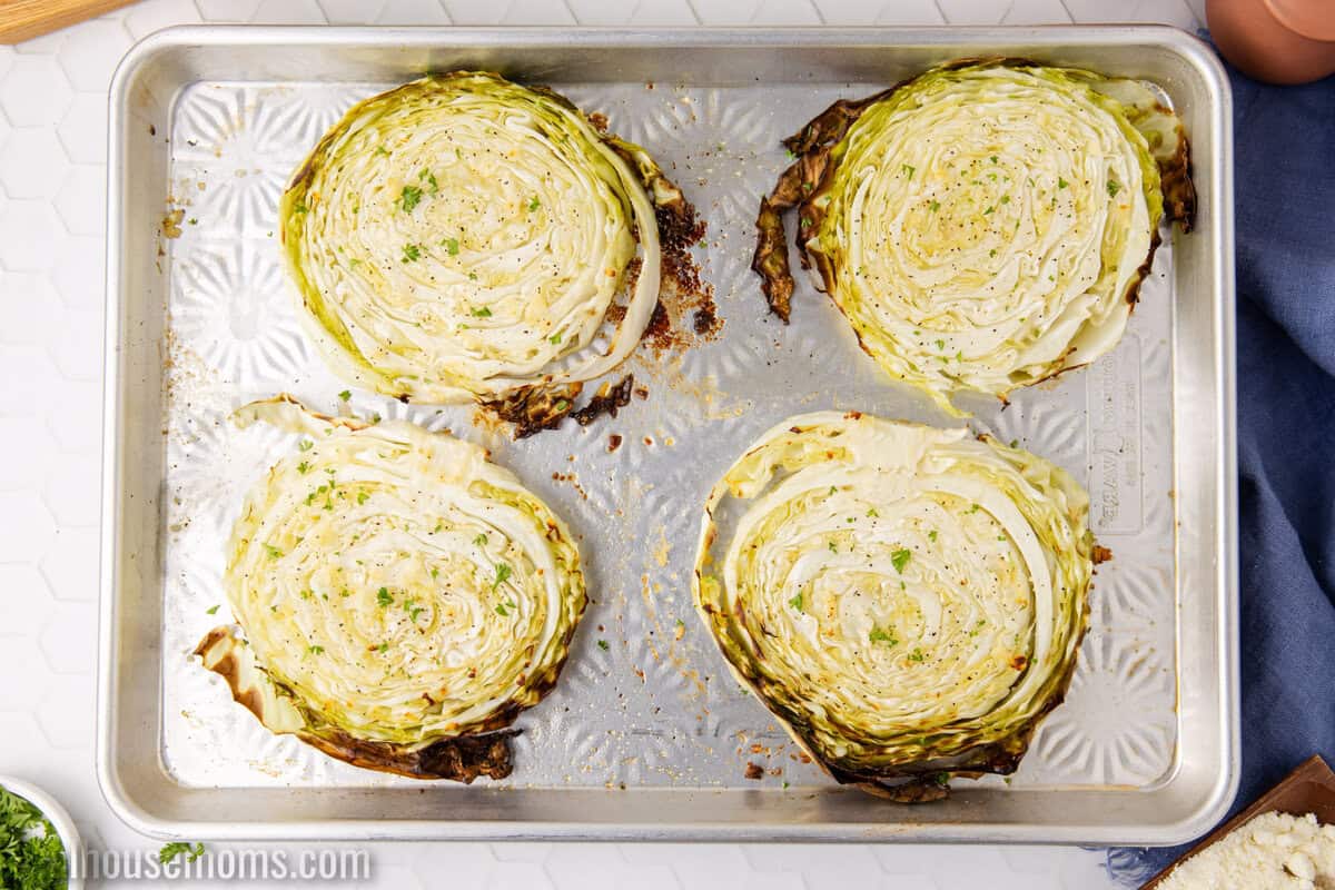 four cabbage steaks on a baking sheet after roasting