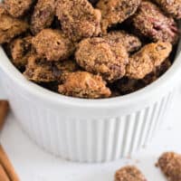 candied pecans and cinnamon sticks in a bowl with recipe name at the bottom