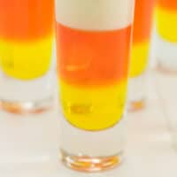 candy corn jello shots in shot glasses with recipe name at the bottom