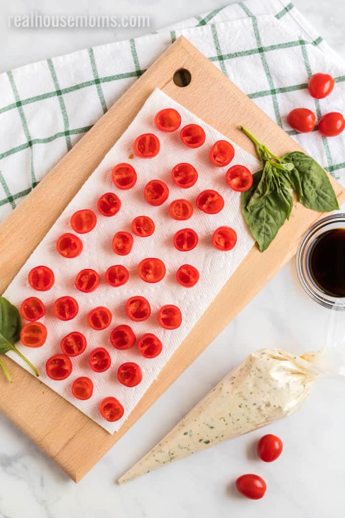 halved cherry tomatoes with a piping bag of herbed mozzarella cheese