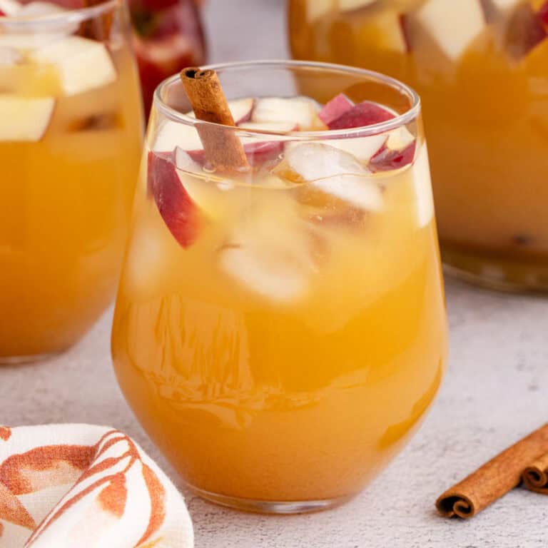 square image of a glass of caramel apple sangria with a cinnamon stick for garnish