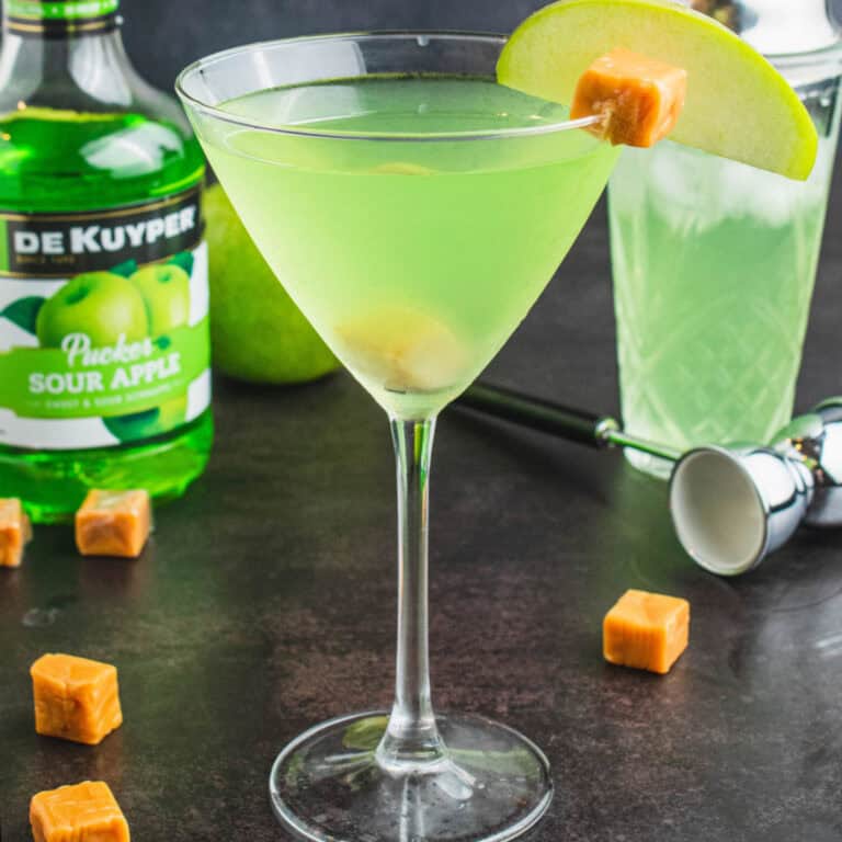 square image of a caramel appletini with an apple slice and caramel square for garnish