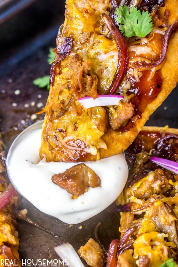 Caramelized Onion and BBQ Pork Flatbread slice being dipped into ranch dressing