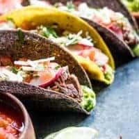 Carne Asada Tacos in hard corn tortilla shells topped with cilantro and radishes