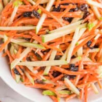 close up of carrot and apple slaw in a bowl with recipe name at the bottom